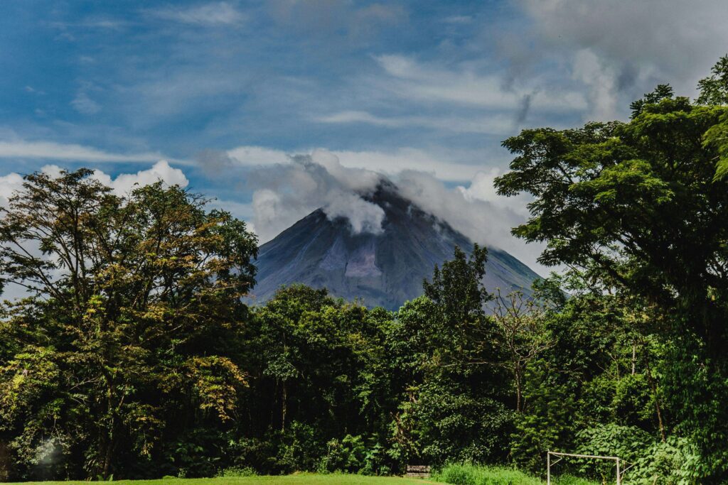Volcanic peak rising above dense Costa Rica rainforest with cloud cover, similar to the forested volcanic landscape surrounding Braulio Carrillo National Park