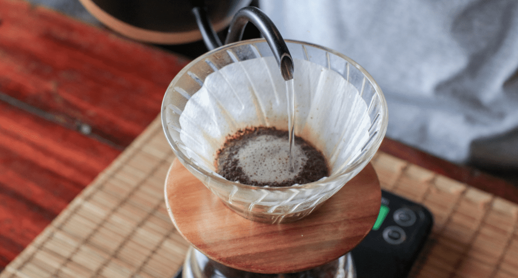 Barista pouring hot water into ground coffee beans. Brewing Filtered drip coffee in cafe