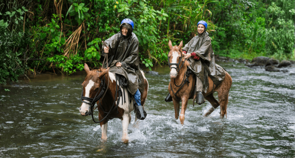 Man and woman galloping in River Arenal during Horseback riding on foot of Volcano Arenal, Costa Rica