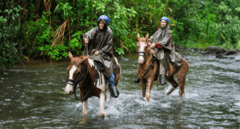 Man and woman galloping in River Arenal during Horseback riding on foot of Volcano Arenal, Costa Rica