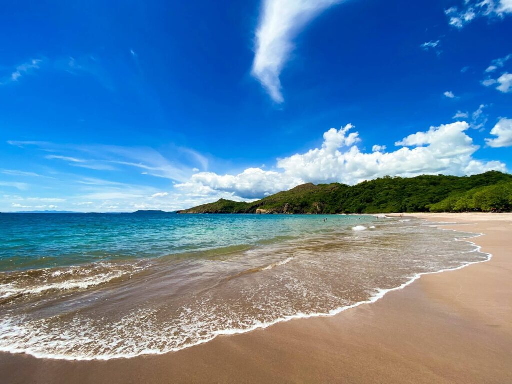 White sand beach with turquoise waters and forested hillside along the coastline, Costa Rica
