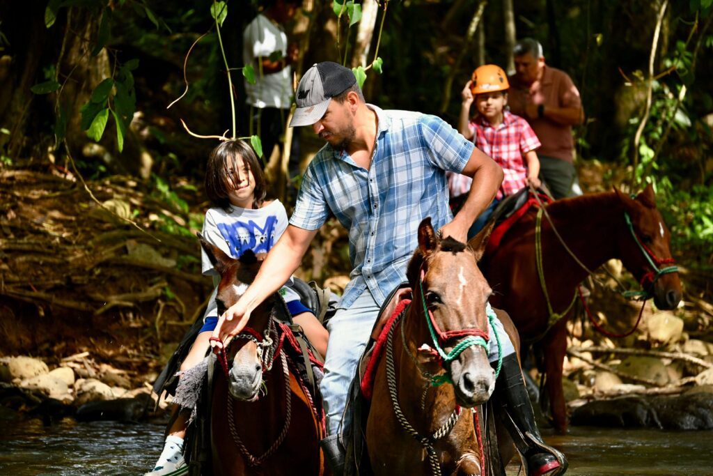 Family horseback riding through Costa Rica rainforest, similar to the return ride included with El Tigre Waterfalls Full Package in Monteverde