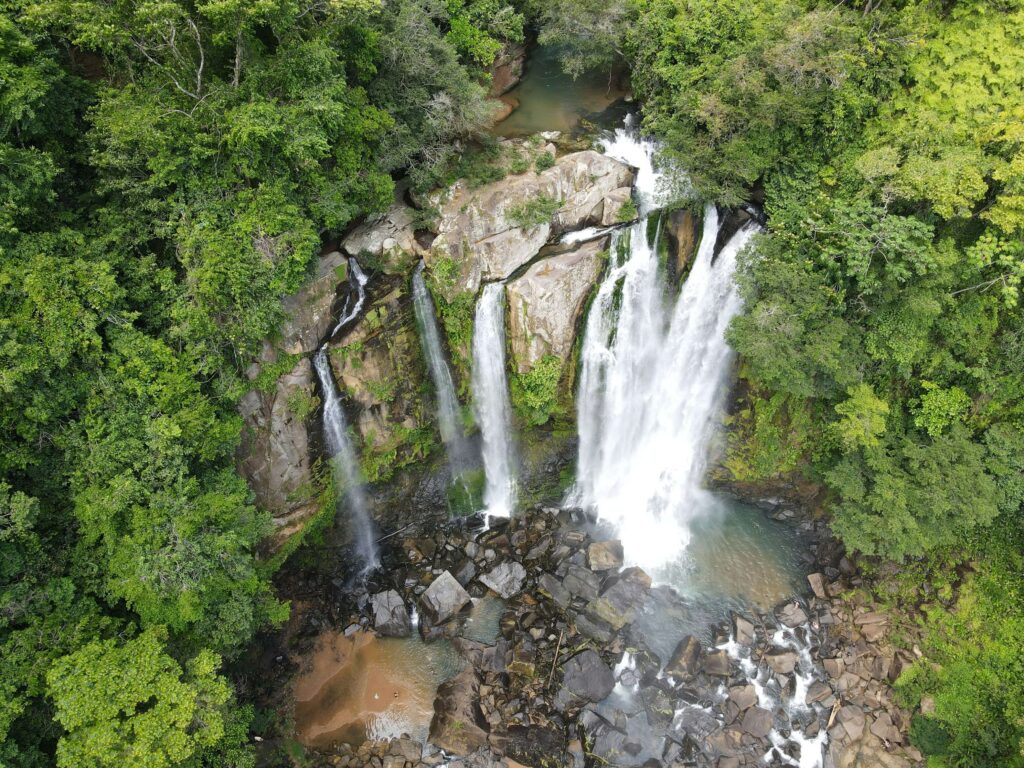 Aerial view of Nauyaca Waterfalls upper cascade dropping over rocky cliffs into jungle pool, Costa Rica