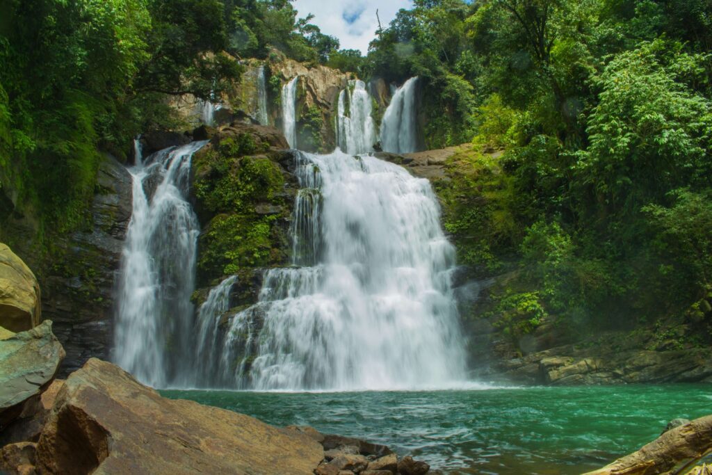 Nauyaca Waterfalls lower cascade with turquoise swimming pool surrounded by rainforest near Dominical, Costa Rica