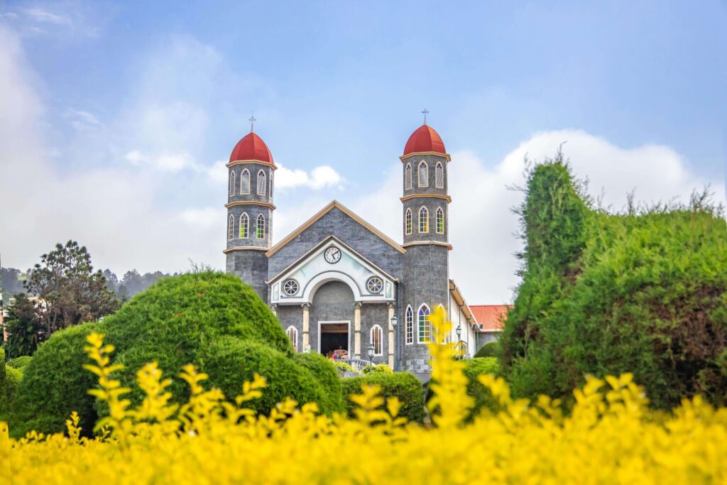 Church in Zarcero, Costa Rica, framed by manicured gardens and yellow flowers.