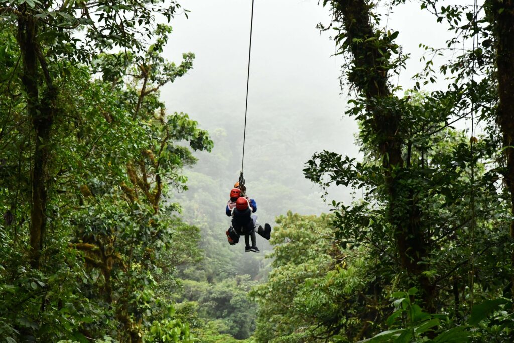 Two people ziplining tandem through the rainforest canopy on a Costa Rica canopy tour