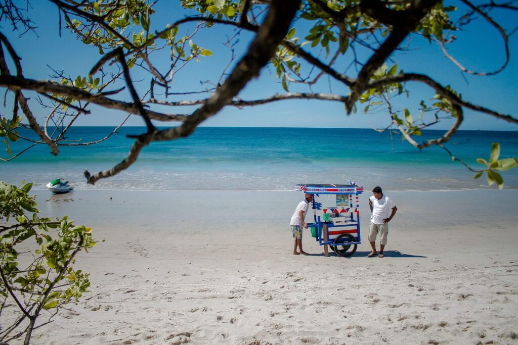 Costa Rican beach vendor cart on white sand with a jet ski on the turquoise water beyond