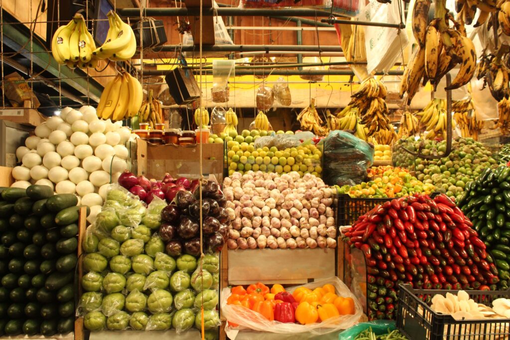 Abundant market stall stacked with garlic, chiles, plantains, and vegetables, similar to San José Central Market, Costa Rica