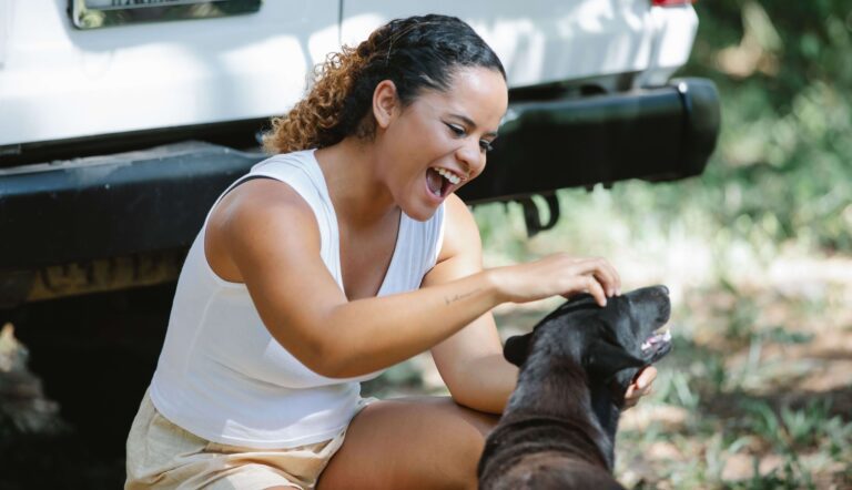 Woman laughing as she pets a happy rescued dog outdoors, similar to meeting the dogs at Territorio de Zaguates, Costa Rica