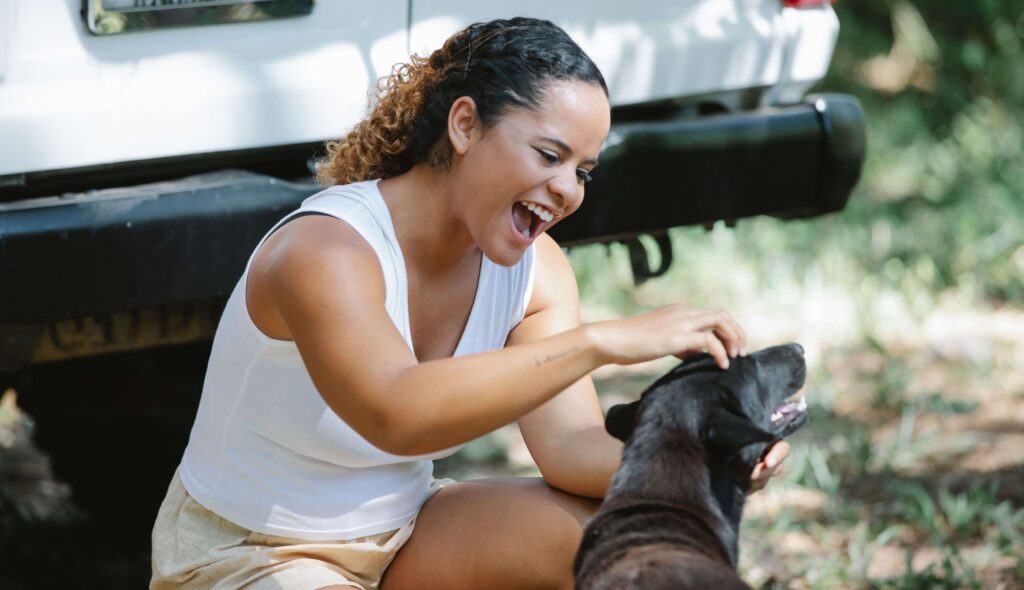 Woman laughing as she pets a happy rescued dog outdoors, similar to meeting the dogs at Territorio de Zaguates, Costa Rica