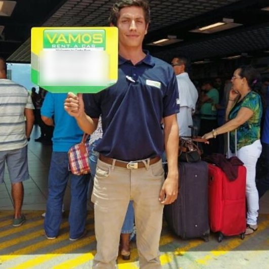 Vamos agent holding a VAMOS welcome sign for arriving travelers
